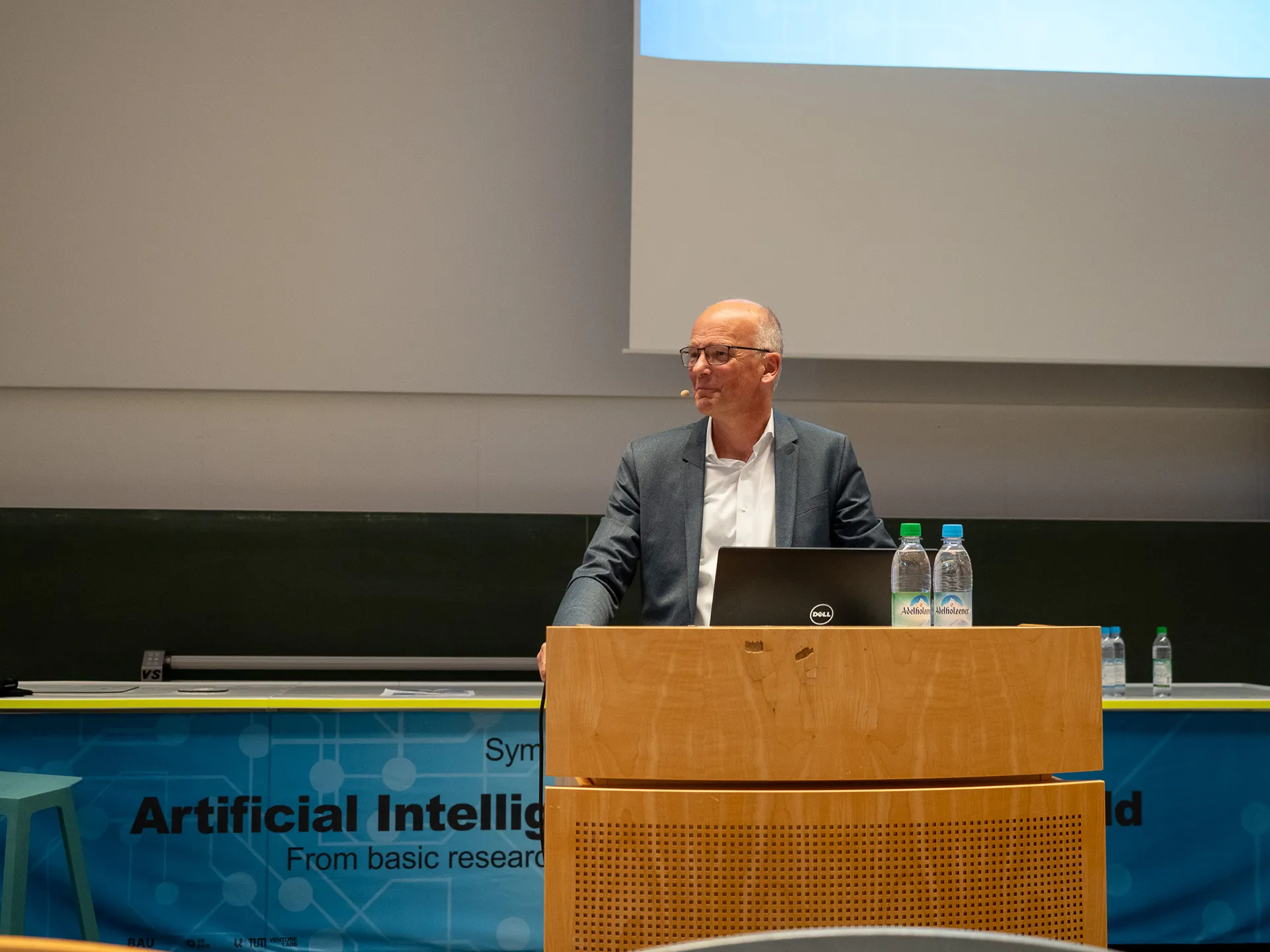 Mann an Speakerpult vor Leinwand